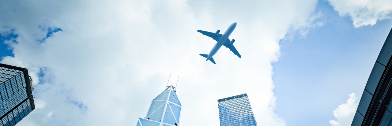 一架飛機在城市飛行； 圖像用於香港滙豐的旅行網絡安全檢查表。